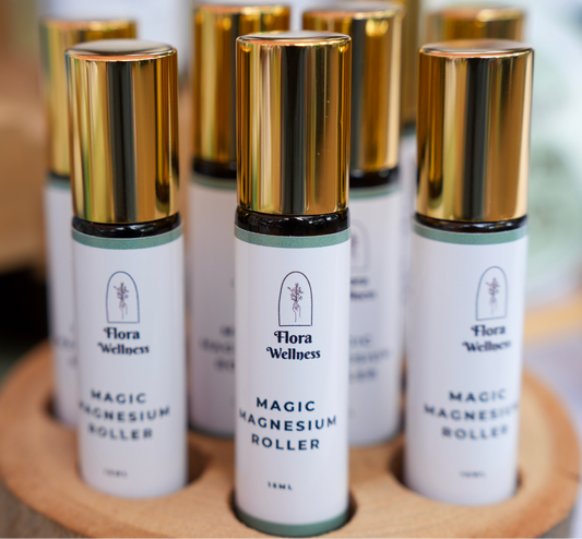 Flora Wellness Magic Magnesium Roller bottles on a wooden stand.